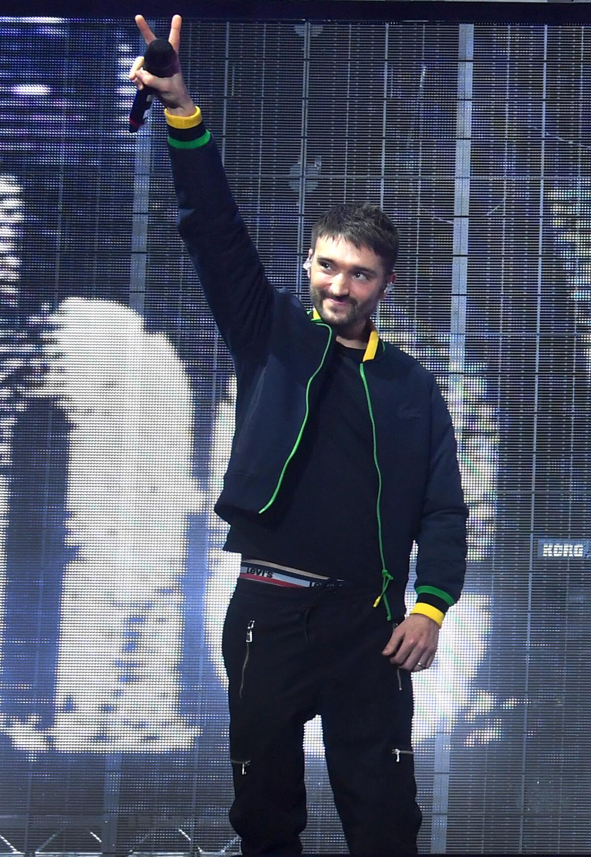 A man onstage holding a microphone up in the air