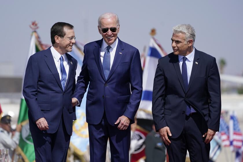 President Joe Biden stands with Israeli Prime Minister Yair Lapid, right, and President Isaac Herzog, left, after arriving at Ben Gurion Airport, Wednesday, July 13, 2022, in Tel Aviv. (AP Photo/Evan Vucci)