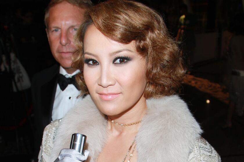 Coco Lee Man wears a silver and gold beaded dress with silver satin gloves, and her husband Bruce Rockowitz wears a tuxedo. 