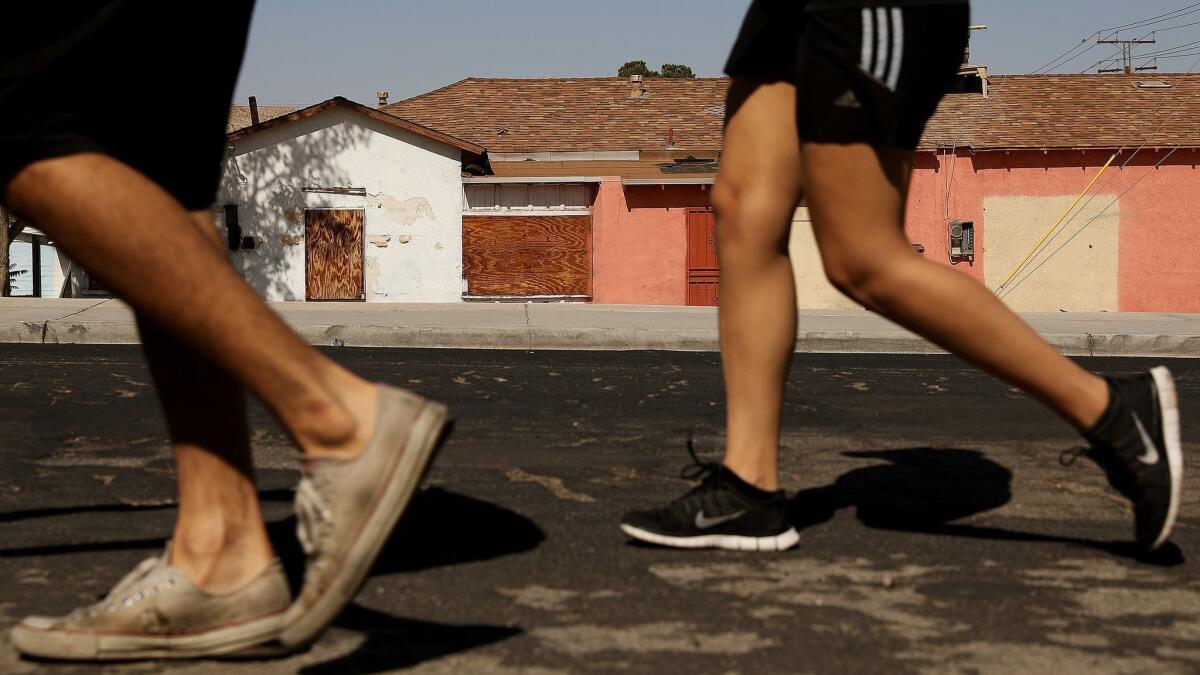 Passersby walk past boarded-up buildings in Old Town Victorville.