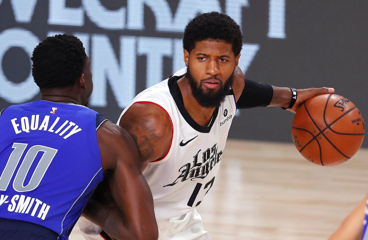 Clippers forward Paul George is defended by Dallas' Dorian Finney-Smith during Game 3 on Aug. 21, 2020.