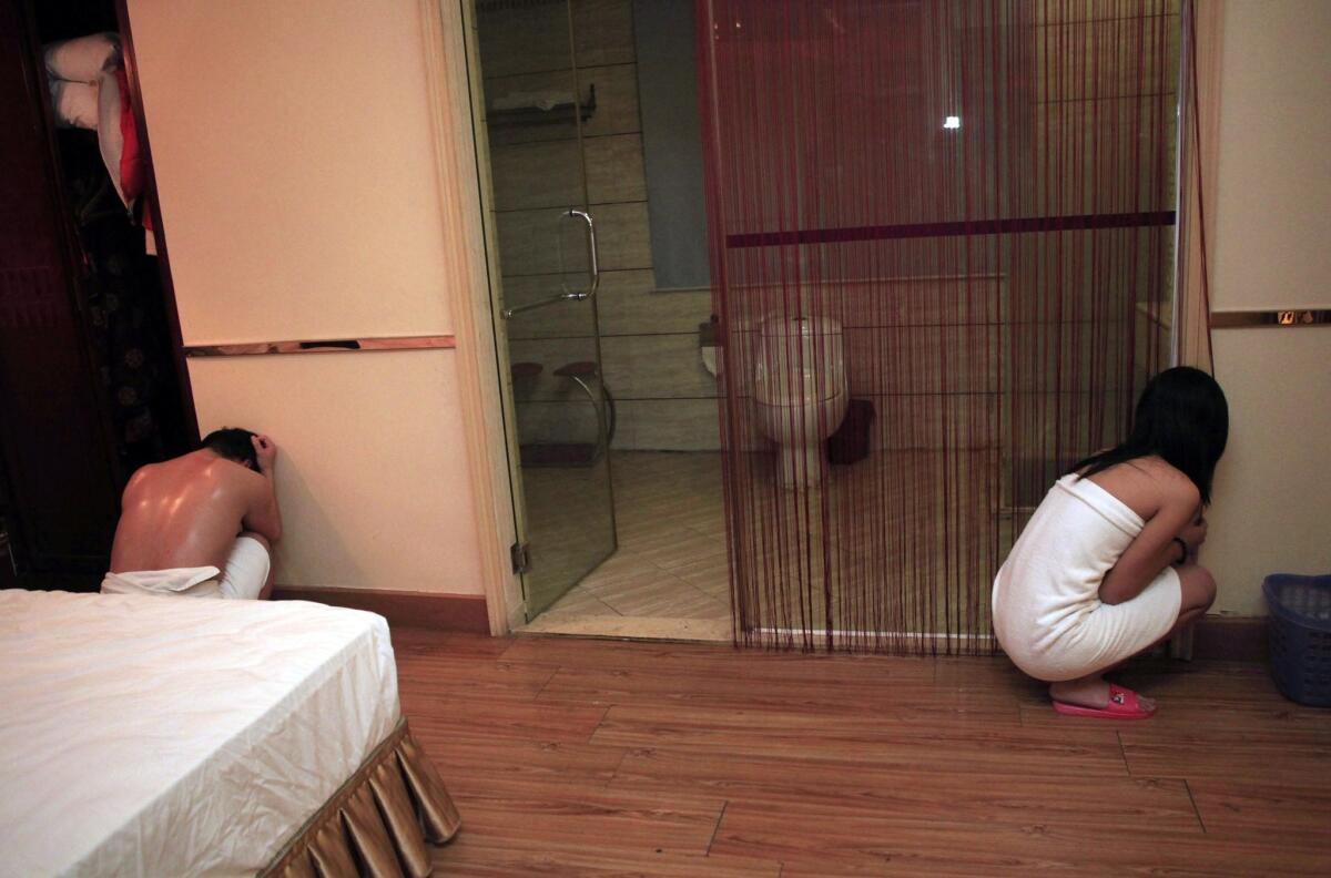 An alleged sex worker and client are shown during a raid on an entertainment center in Dongguan, in southern China's Guangdong province.