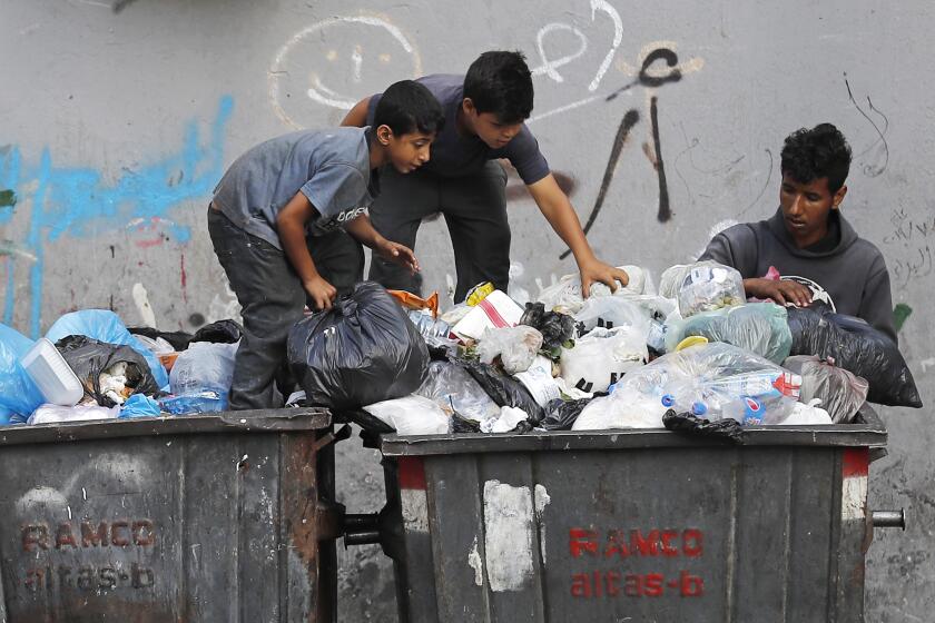 FILE - Boys scavenge in a dumpster for valuables and metal cans that can be resold, in Beirut, Lebanon, June 17, 2021. As Lebanon faces one of the world’s worst financial crises in modern history, now even its trash has become a commodity fought over in the street. (AP Photo/Hussein Malla, File)
