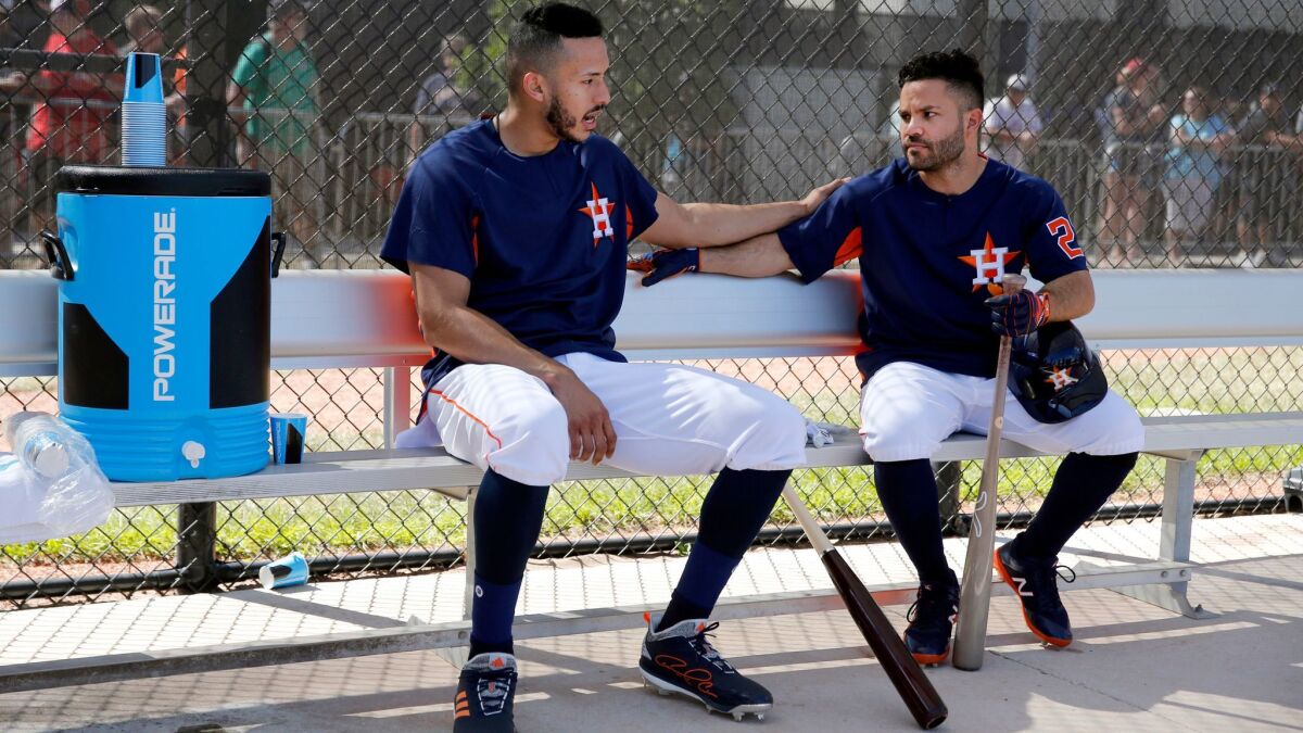 The Astros' Carlos Correa, left, and Jose Altuve chat in the dugout before taking batting practice during spring training baseball practice Monday, Feb. 19, 2018, in West Palm Beach, Fla.