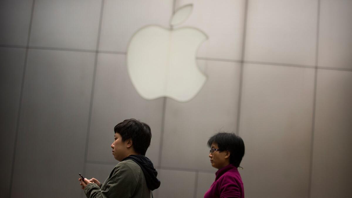 Shoppers walk past an Apple Store at a mall in Beijing on Friday.
