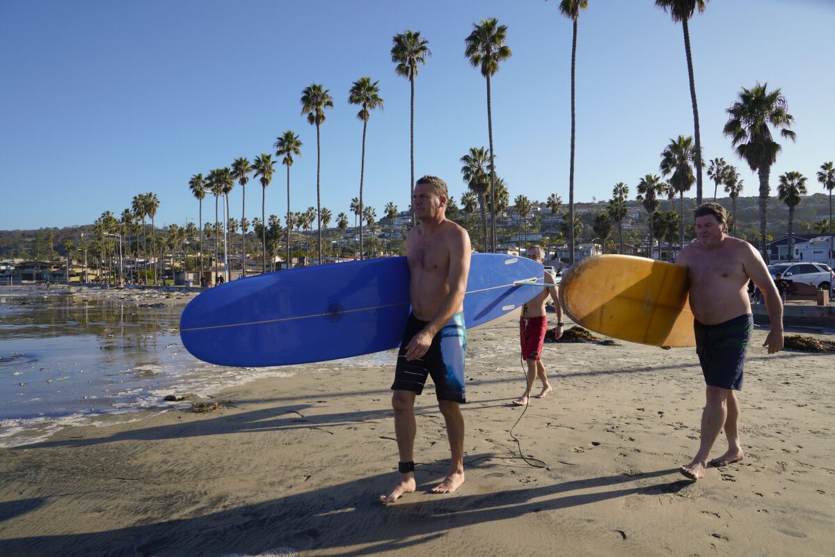Jim Frager, Erik Gantzel and Tim Wright (from left) head into the surf at La Jolla Shores on Jan. 1 without their wetsuits.