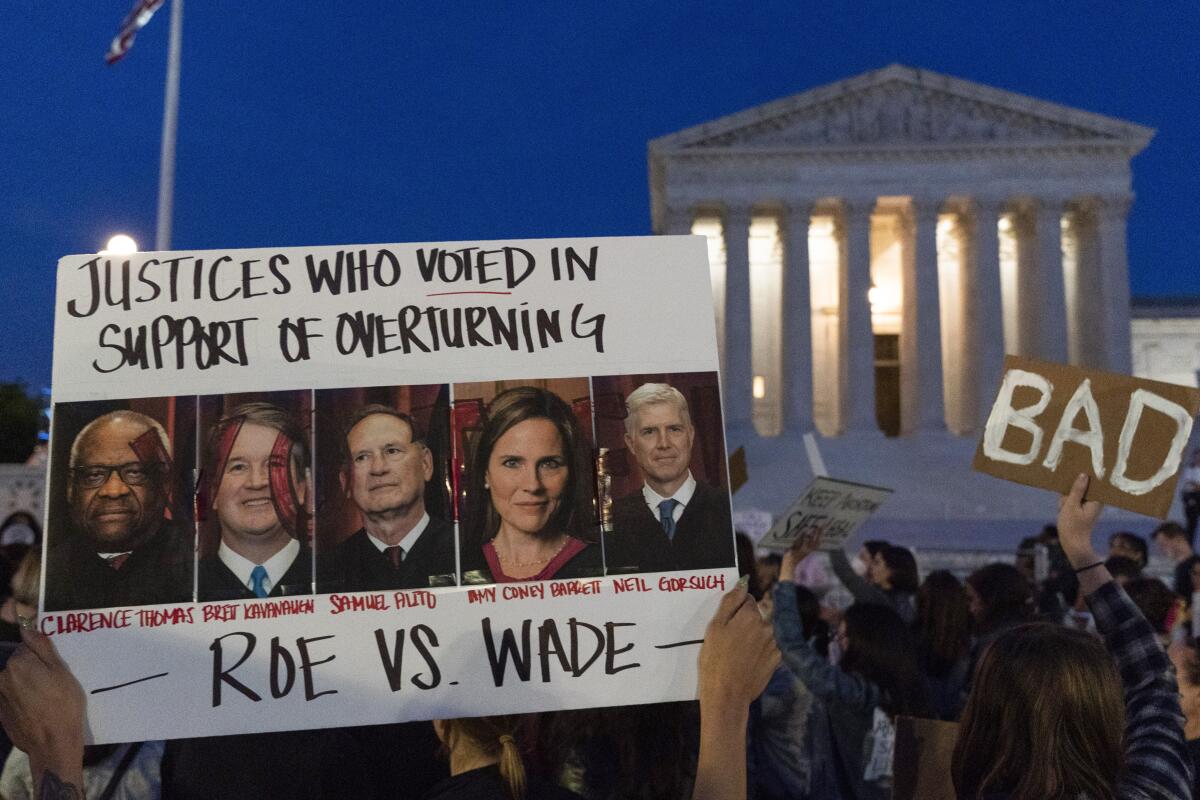 A protester holds a poster with photos of the Supreme Court justices who voted to overturn Roe vs. Wade