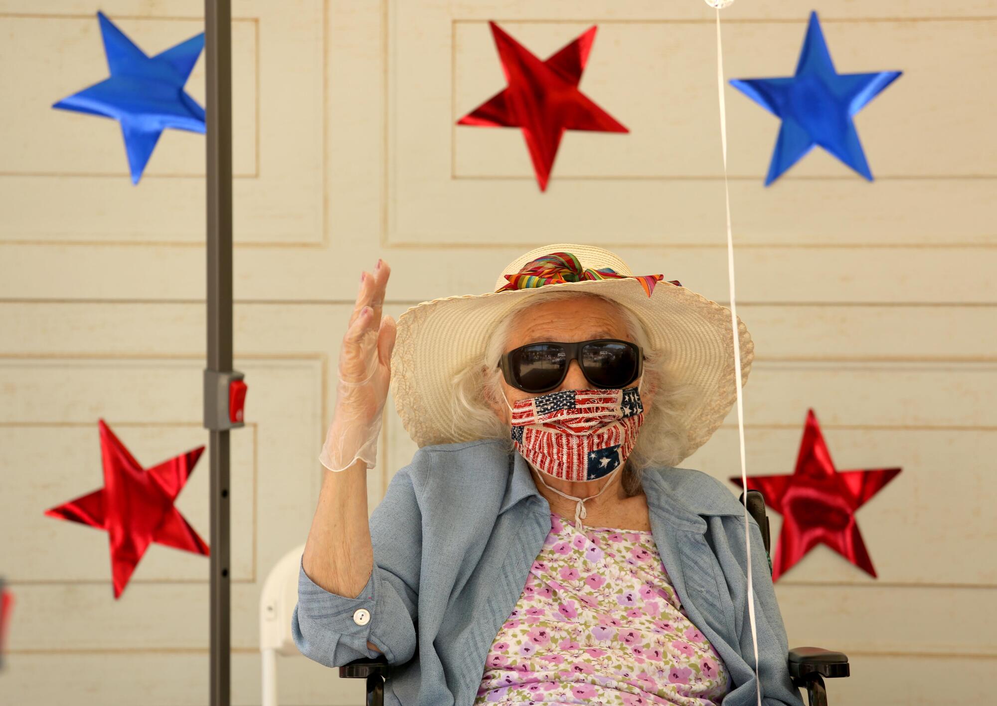 A resident of Mom & Dad's House waves while members of the public drive by to celebrate World War II veteran Lt. Col. Sam Sachs' 105th birthday.