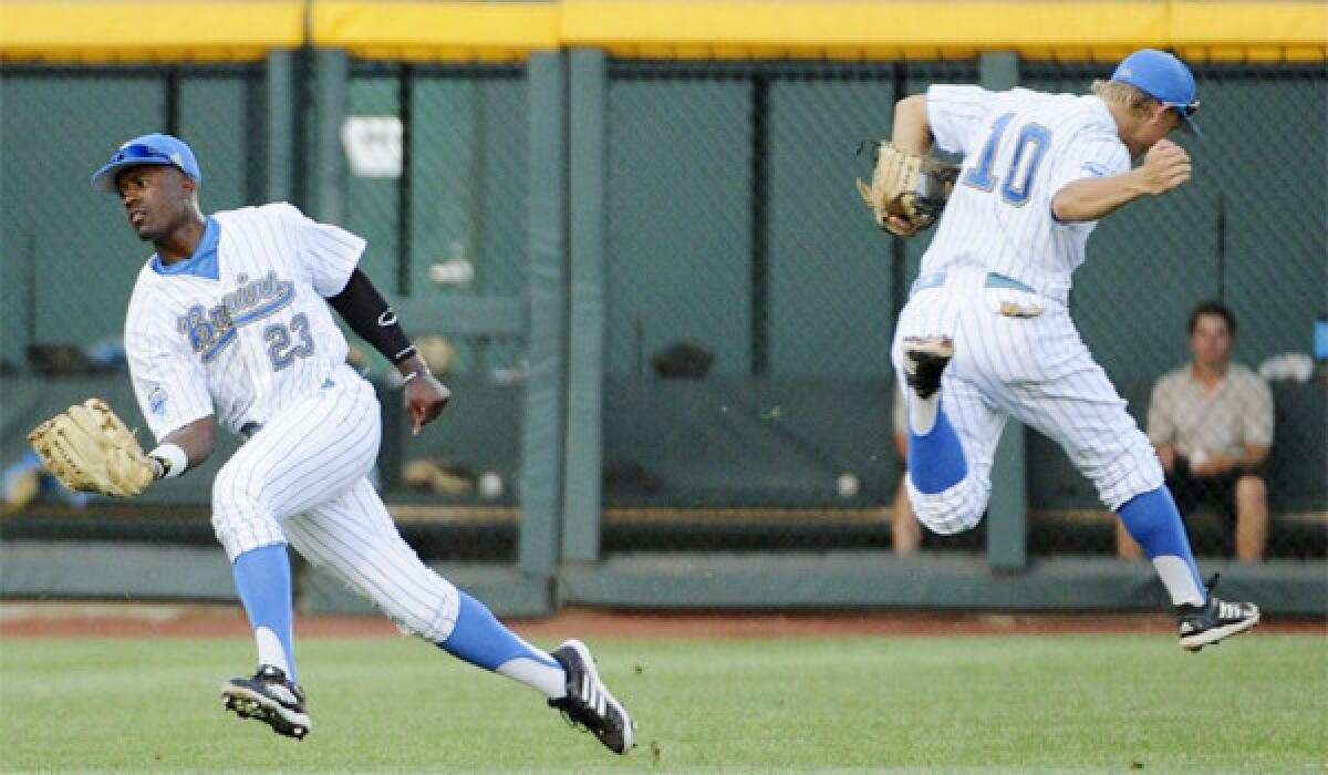 UCLA left fielder Brenton Allen, left, catches a fly ball as shortstop Pat Valaika runs in the opposite direction in the third inning of the Bruins' 4-1 victory over the Tarheels, punching their ticket for the College World Series championship round where they'll face Mississippi State.