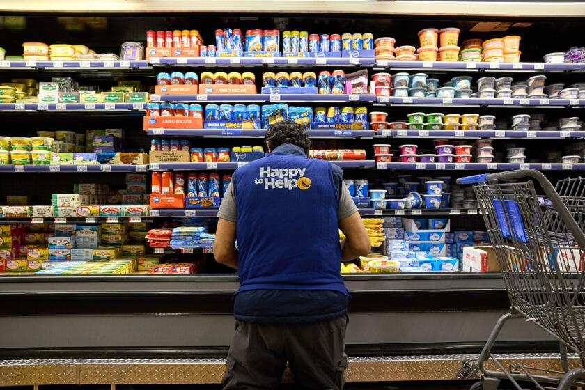 A worker stocks a shelf in a grocery aisle at a Walmart store. Photographer: Brian Kaiser/Bloomberg