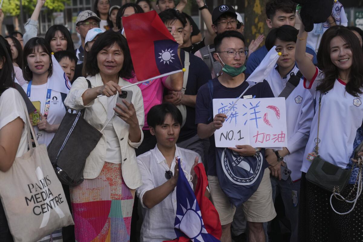 Fans display the flags of Taiwan as they cheer outside Porte de la Chapelle Stadium after Taiwan beat China in badminton