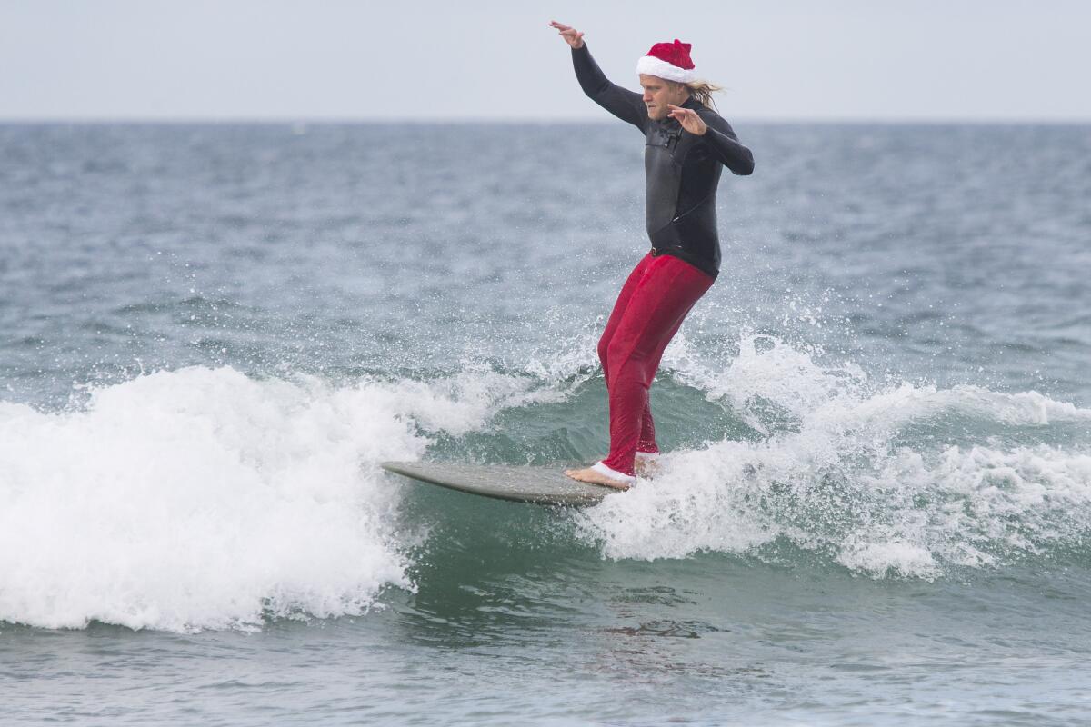 Adam Thomson surfs while wearing a Santa Claus hat.