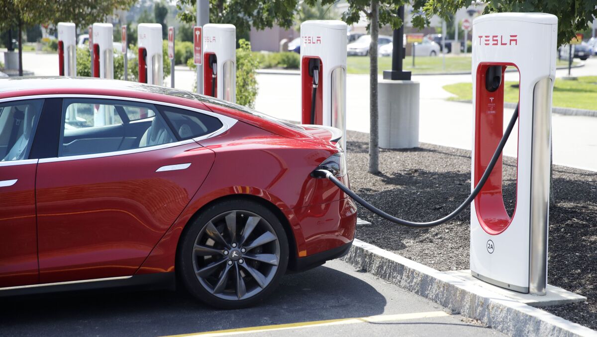 FILE - A Tesla Model S is plugged in at a vehicle Supercharging station in Seabrook, N.H., Aug. 24, 2018. The driver of a Tesla operating on autopilot must stand trial for a crash that killed two people in a Los Angeles suburb, a judge ruled Thursday, May 19, 2022. There is enough evidence to try Kevin George Aziz Riad, 27, on two counts of vehicular manslaughter in a 2019 crash, a Los Angeles County judge said. (AP Photo/Charles Krupa, File)