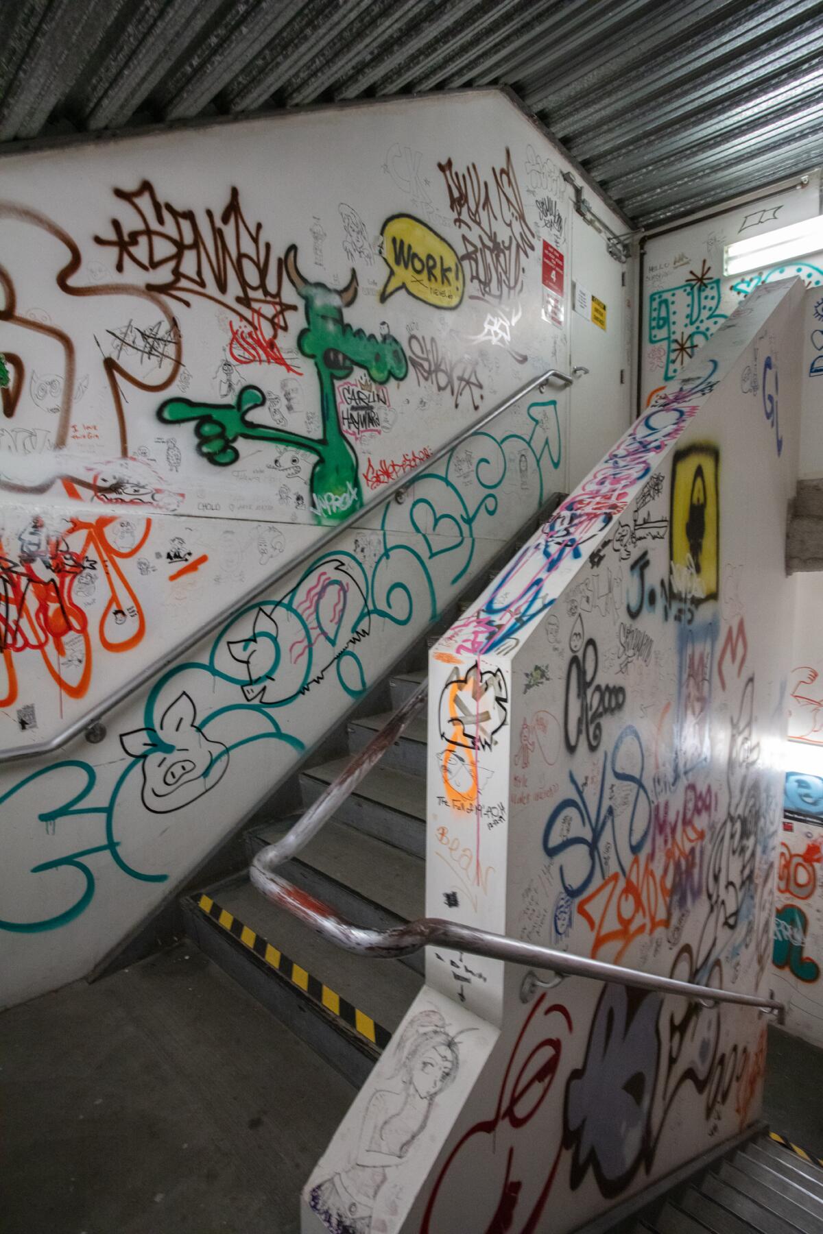 white walls in a stairwell covered in graffiti and drawings 