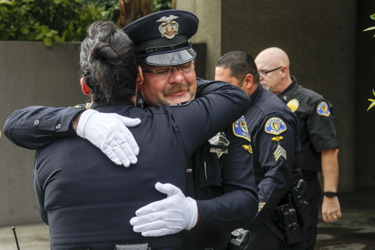 Whittier Police Officer Richard Jensen is comforted by other officers at Rose Hill Memorial Park.