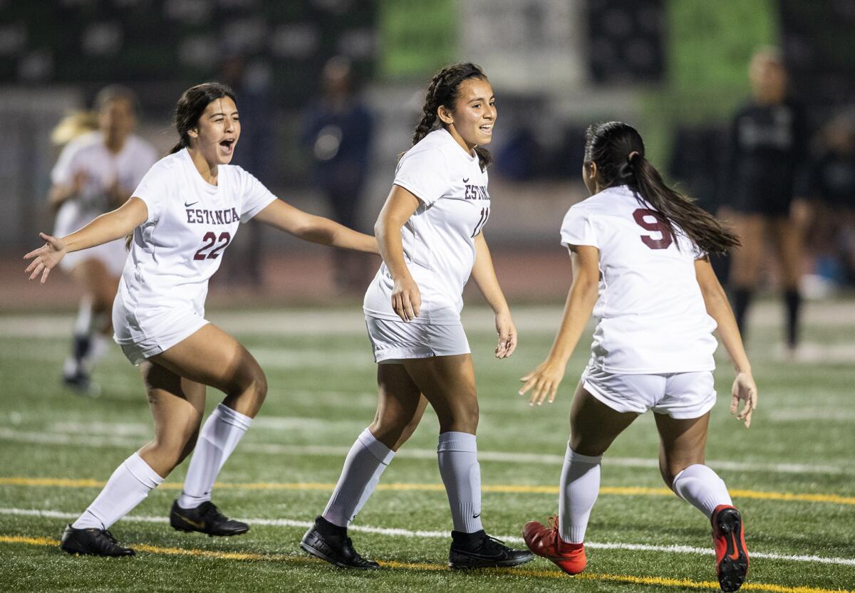 Estancia's Alyssa Garrett, left, and Desiree Mendoza, right, celebrate with Merlin Serpas after Serpas scored a goal in the 28th minute of an Orange Coast League match on Tuesday.