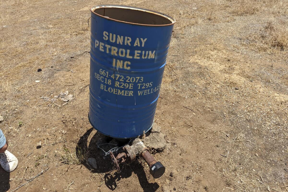 A blue barrel protects a well cap apparatus in an area surrounded by bare dirt
