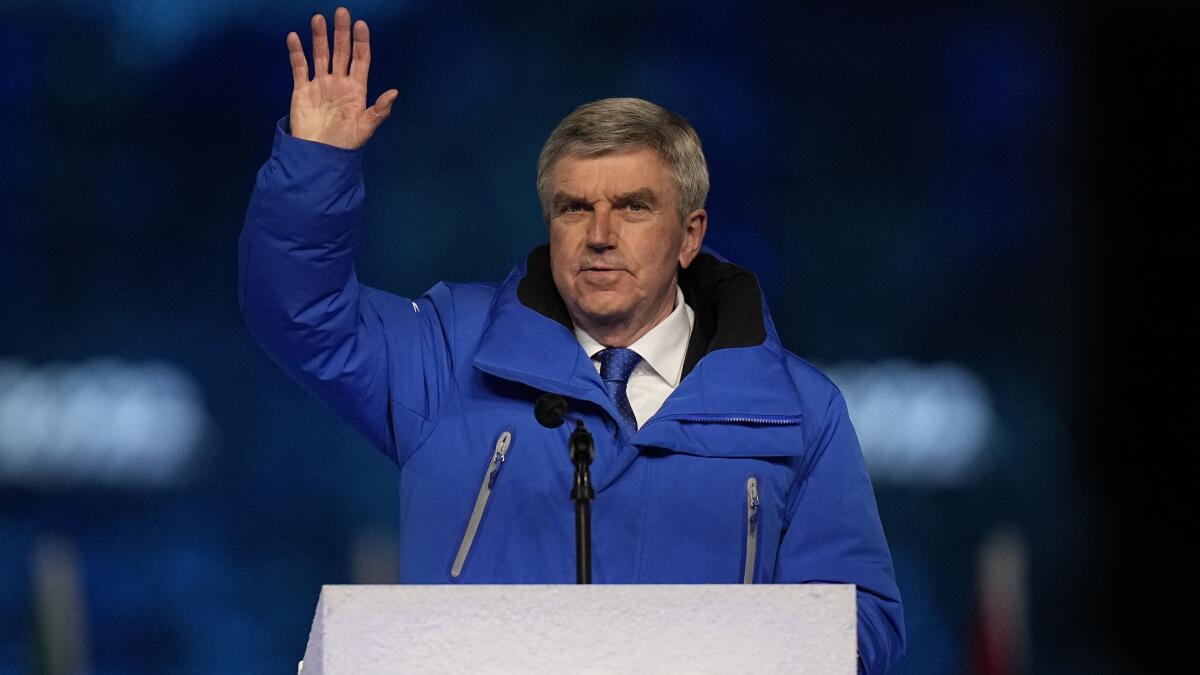 The IOC's Thomas Bach waves from a lectern during the closing ceremony of the 2022 Olympics.