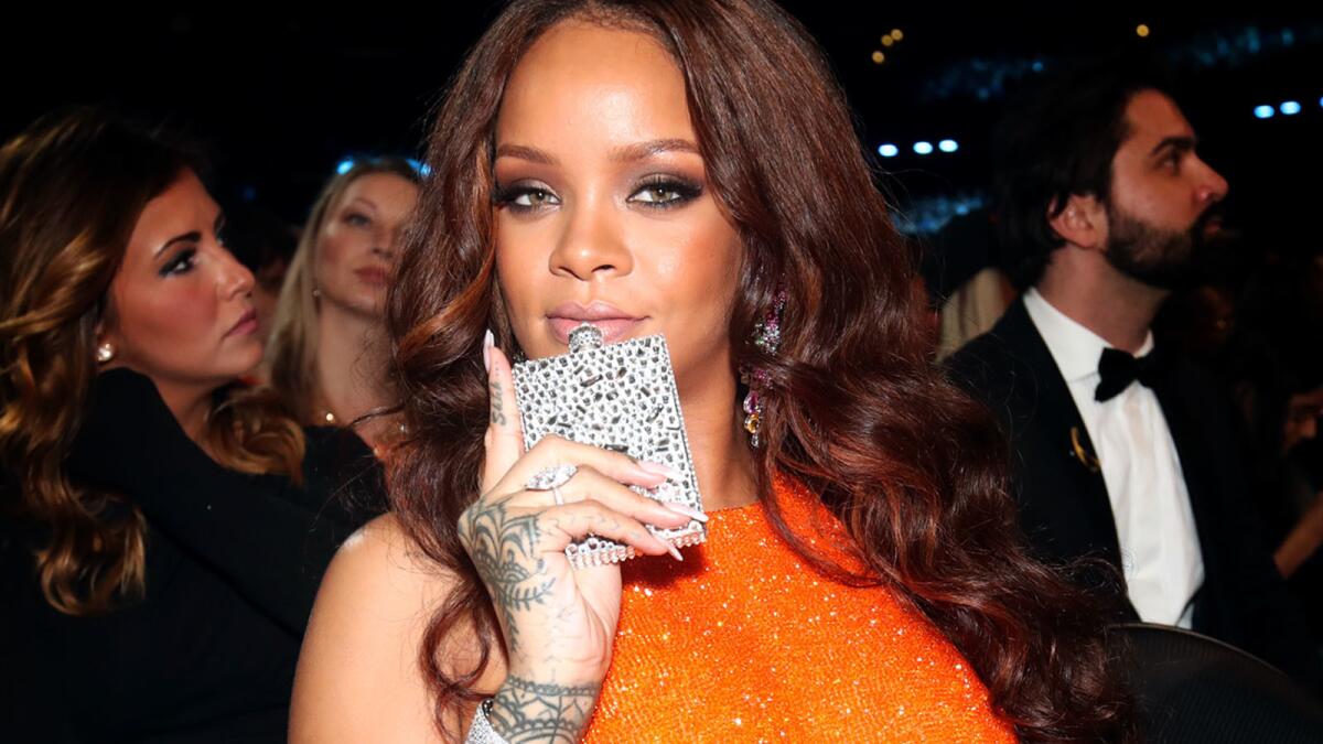 Rihanna, bejeweled flask in hand, strikes a pose for a party photographer.
