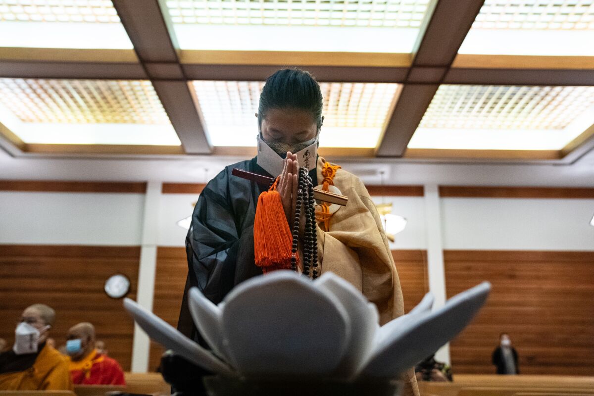 A woman prays with beads in hand in a Buddhist temple
