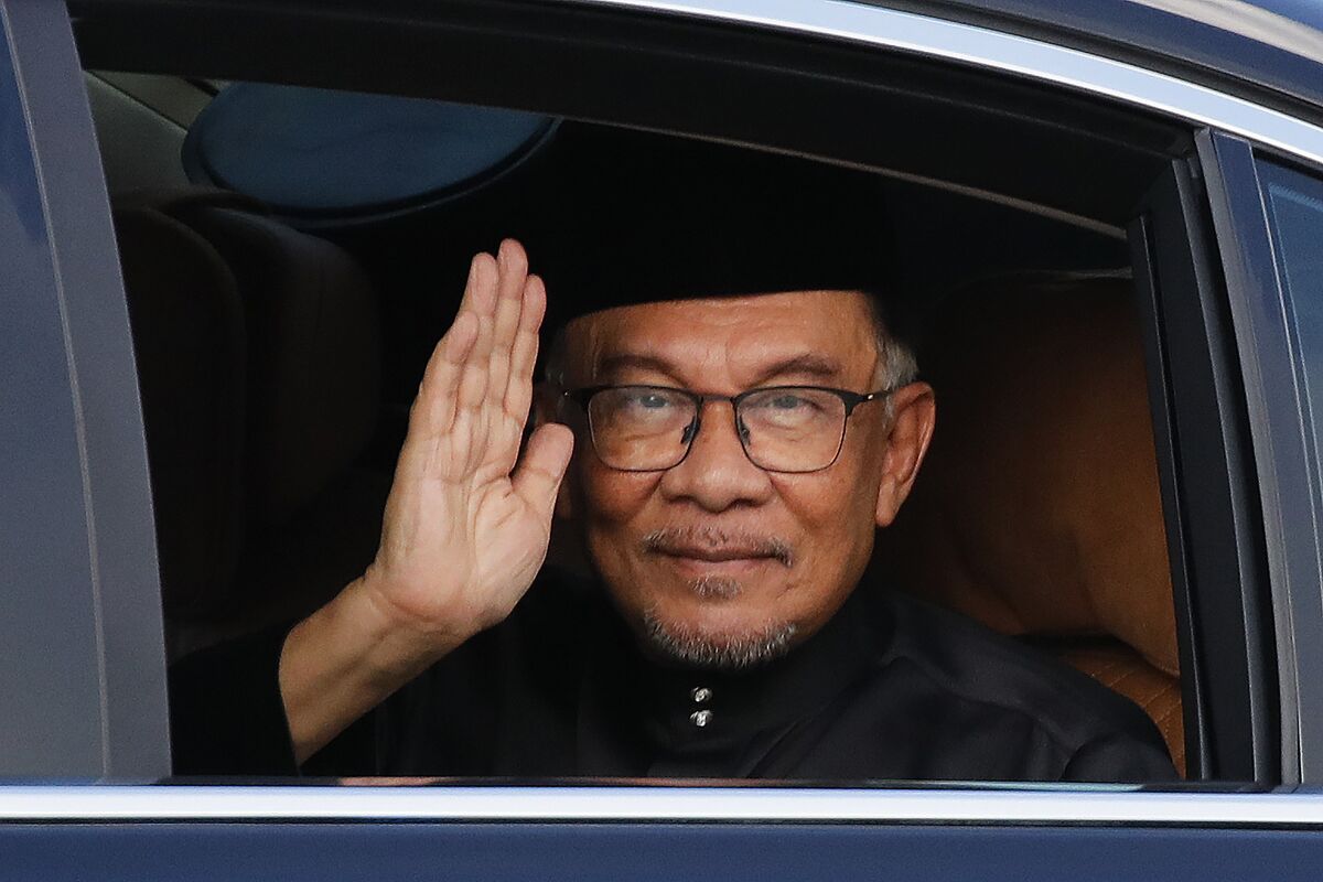 Newly appointed Malaysian Prime Minister Anwar Ibrahim waves from a car window