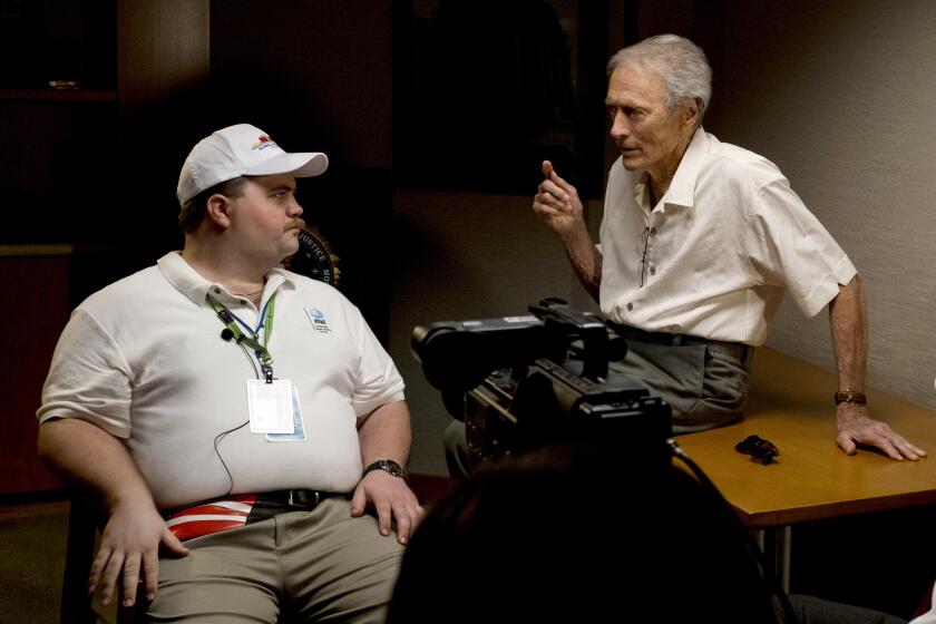 In this image released by Warner Bros. Pictures, director Clint Eastwood speaks with actor Paul Walter Hauser as they work during the filming of the movie "Richard Jewell." When a bomb exploded in a downtown Atlanta park midway through the 1996 Olympics, it set news reporters and law enforcement on a collision course that upended the life of a security guard, turning him from hero to villain overnight. Now, more than 20 years later, a recent book and upcoming movie explore Jewell's ordeal and the roles played by law enforcement and the media. (Claire Folger/Warner Bros. Pictures via AP)