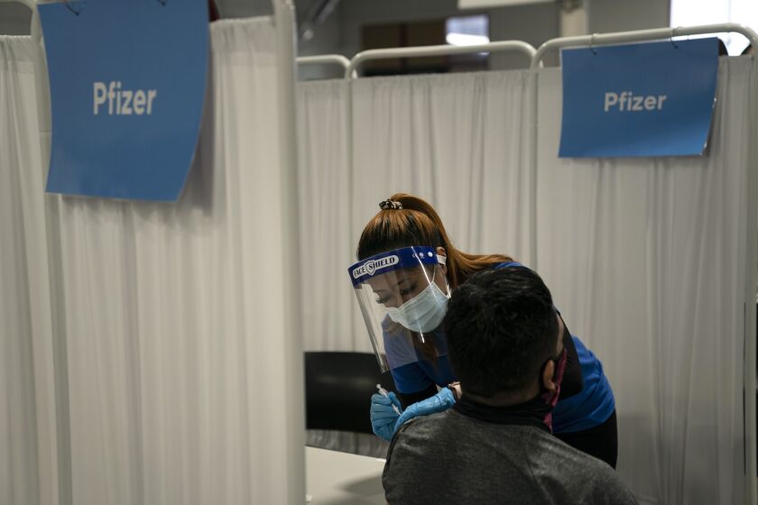 A nurse administers the Pfizer COVID-19 vaccine to a patient in Santa Ana, Calif.