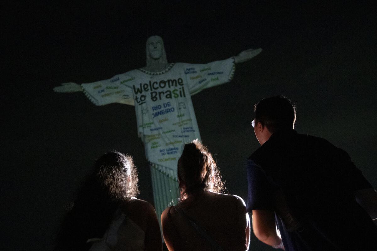 Fanáticos miran la estatua del Cristo Redentor iluminada con un mensaje de bienvenida para Taylor Swift