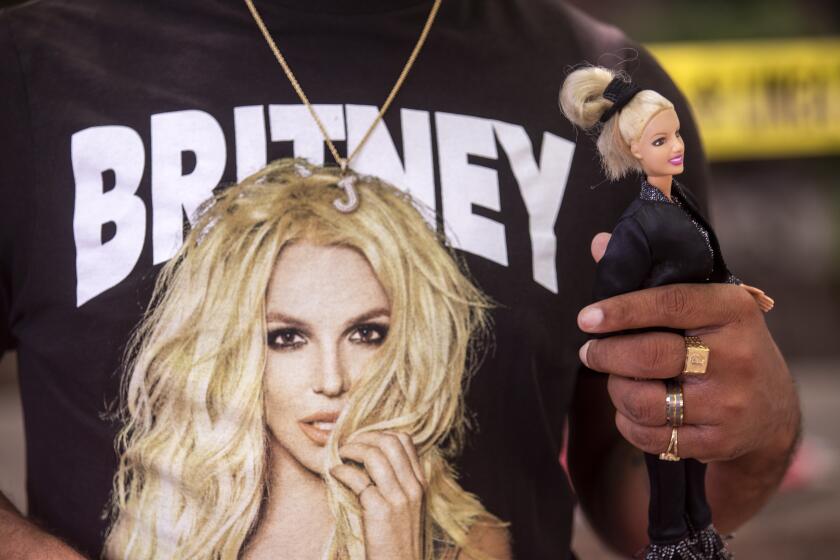 LOS ANGELES, CA - JULY 14: Derrick Daniels, 32, of Las Vegas is holding a Britney Spears doll and is part of a crowd of about 150 people supporting Britney Spears stood outside a courthouse, holding signs and chanting in Los Angeles, CA today. Britney Spears' conservatorship case resumes after last month's explosive testimony on Wednesday, July 14, 2021. A crowd of about 150 people supporting Britney Spears stood outside a courthouse, holding signs and chanting.The singer's personal and financial affairs have been monitored by a judge since early 2008, when she exhibited bizarre public behavior. Spears recently told a judge she wants the conservatorship ended. She was not at this court house. (Francine Orr / Los Angeles Times)