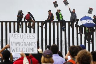 Central American migrants and their supporters sat on top of the border wall during a rally in support of the migrants on Sunday, April 29, 2018. Groups on both sides of the border gathered at Border Field State Park before the asylum seekers planned to try to enter the United States. (Photo by K.C. Alfred/ San Diego Union -Tribune)