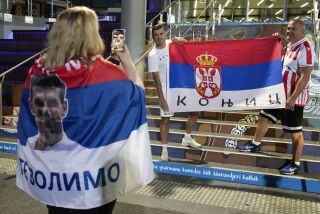 Simpatizantes de Novak Djokovic muestran banderas serbias frente a la Arena Rod Laver de Melbourne, Australia, el viernes 27 de enero de 2023 (AP Foto/Ng Han Guan)