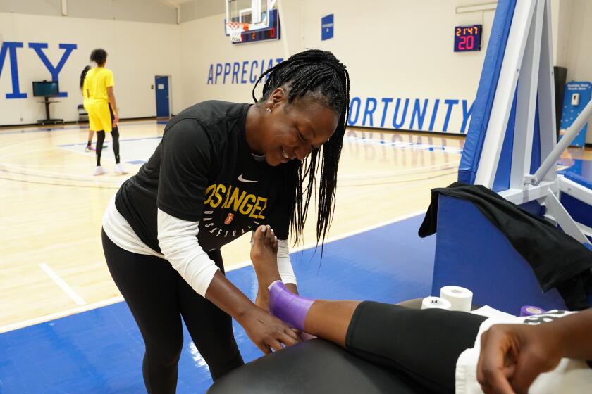 Head athletic trainer Courtney Watson tapes the ankle of a Sparks player.