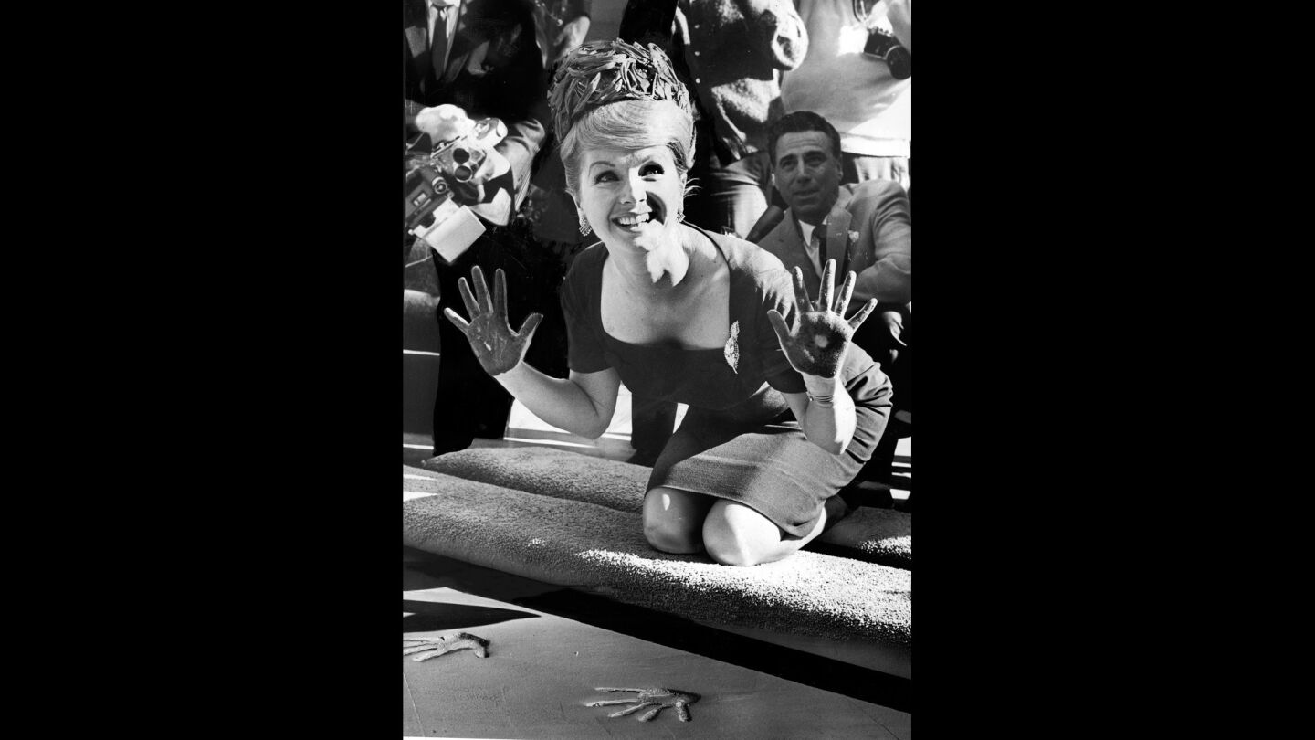 Actress Debbie Reynolds smiles and spreads cement-covered hands after making imprint in forecourt of Grauman's Chinese Theatre on Jan. 14, 1965.