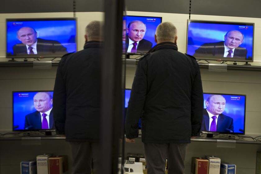 A man watches Russian President Vladimir Putin on TV screens in an electronic hypermarket in Moscow, Russia, Thursday, Dec. 18, 2014. The Russian economy will rebound and the ruble will stabilize, Russian President Vladimir Putin said Thursday at his annual press conference, he also said Ukraine must remain one political entity, voicing hope that the crisis could be solved through peace talks. (AP Photo/Alexander Zemlianichenko)