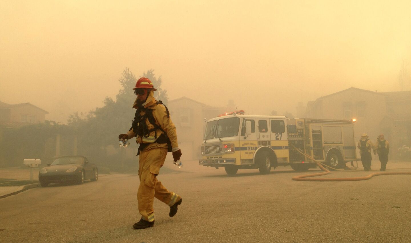 Firefighters move into position in the smoke-choked Dos Vientos neighborhood of Newbury Park as the Springs fire advances.