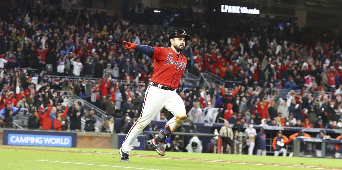 Atlanta Braves' Travis d'Arnaud points at the dugout while rounding the bases on his solo home run in the eighth inning against the Houston Astros in Game 3 of the baseball World Series on Friday, Oct. 29, 2021, in Atlanta. (Curtis Compton/Atlanta Journal-Constitution via AP)