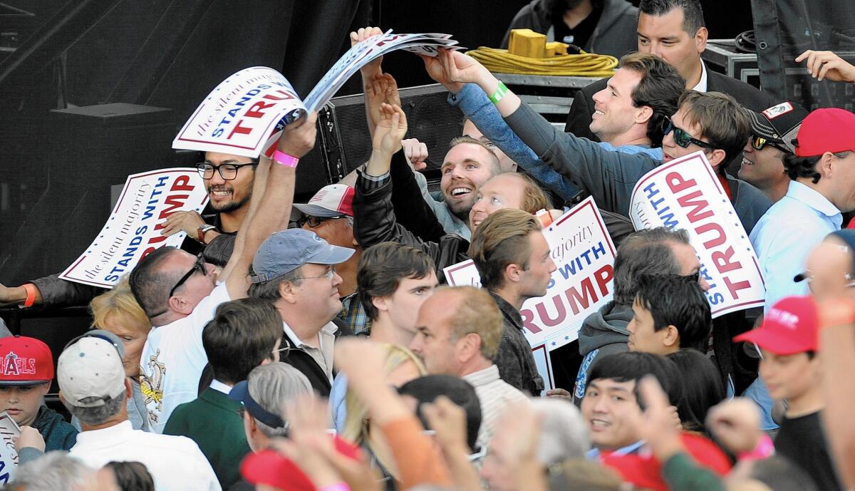 Trump supporters grab signs before his rally in Costa Mesa.