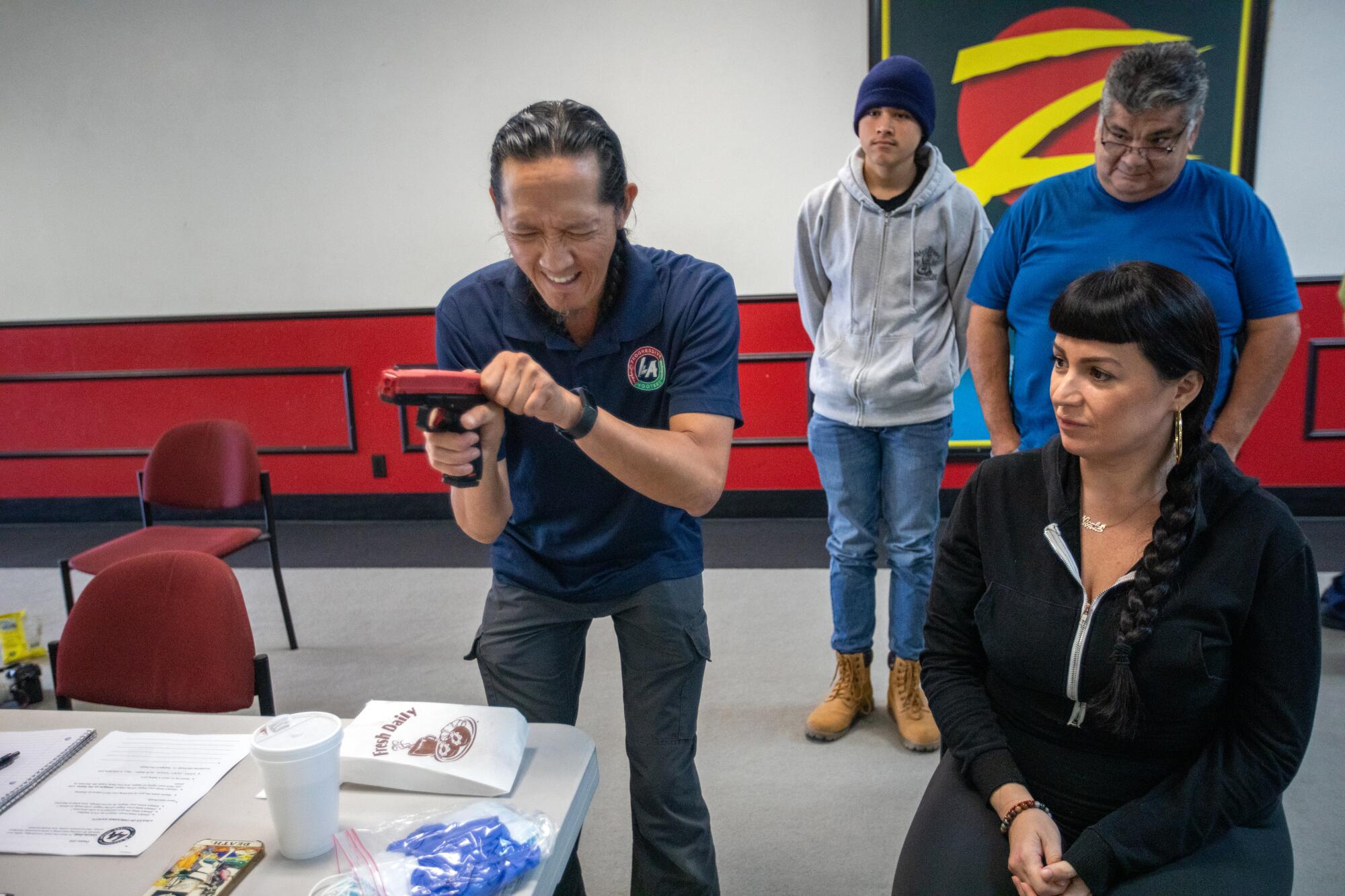 Tom Nguyen, left, grips a Glock replica as three students look on