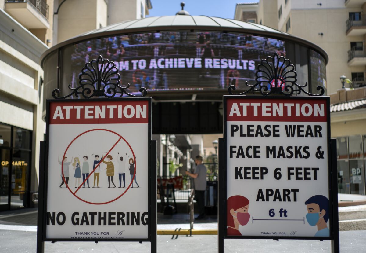 FILE - Signs with social distancing guidelines and face mask requirements are posted at an outdoor mall amid the COVID-19 pandemic in Los Angeles, on June 11, 2021. California is bringing back a statewide indoor mask mandate. Calidfornia Gov. Gavin Newsom's administration announced the new mandate will start Wednesday, Dec. 15, 2021, and last until Jan. 15. The order comes as the per capita rate of new coronavirus cases in California has jumped 47% in the past two weeks. (AP Photo/Damian Dovarganes, File)