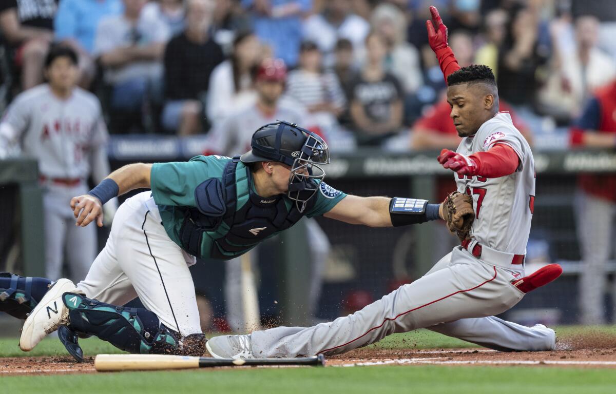 Seattle Mariners catcher Cal Raleigh tags out Los Angeles Angels' Magneuris Sierra at home plate after Sierra attempted to stretch a triple to an inside-the-park home run during the second inning of a baseball game Friday, Aug. 5, 2022, in Seattle. (AP Photo/Stephen Brashear)