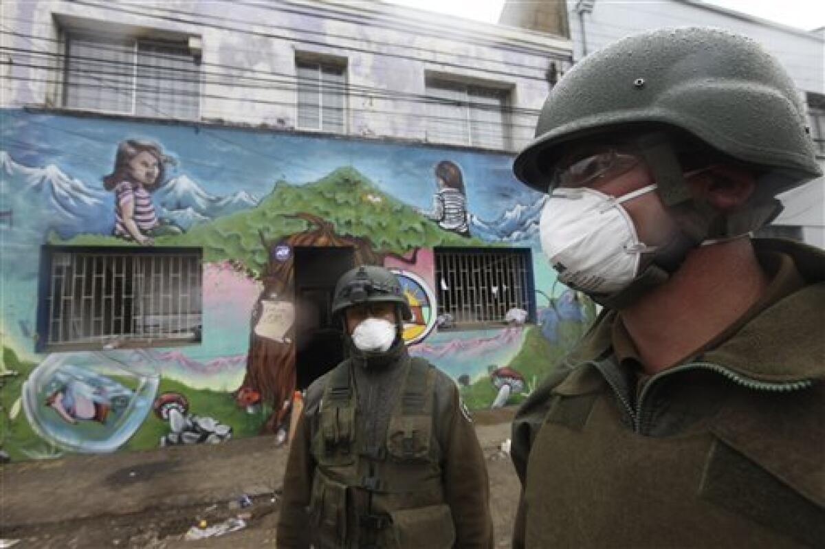 Soldiers wear masks as they patrol near a school in Talcahuano, Chile, Sunday, March 7, 2010. An 8.8-magnitude earthquake struck central Chile on Feb. 27, causing widespread damage. (AP Photo/Silvia Izquierdo)