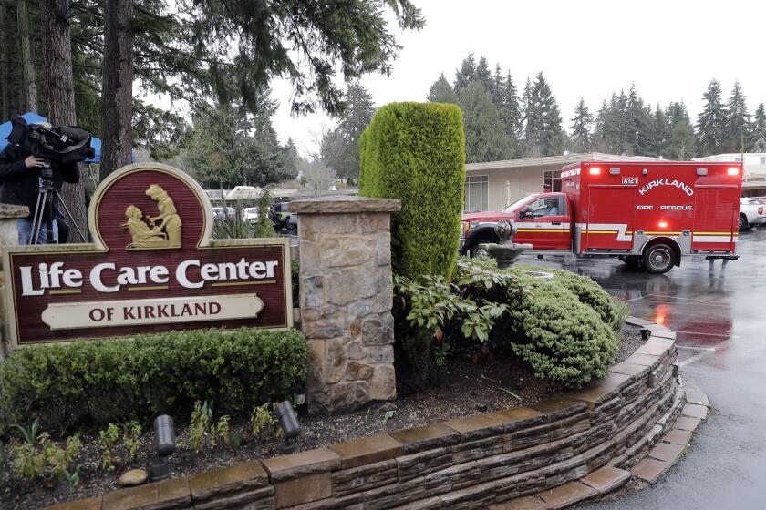 An ambulance backs into a parking lot, Friday, March 6, 2020, at the Life Care Center in Kirkland, Wash., which has become the epicenter of the COVID-19 coronavirus outbreak in Washington state. This ambulance left the facility after a short time and did not transport a patient. (AP Photo/Ted S. Warren)