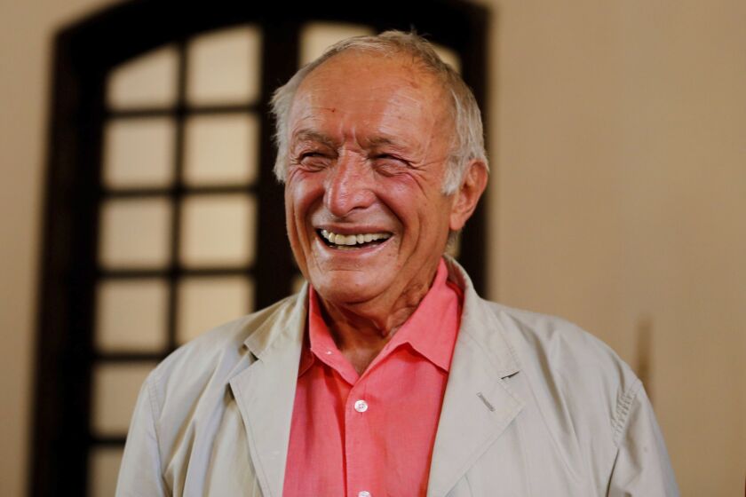 Richard Rogers is seen smiling in a pink shirt and sand colored jacket