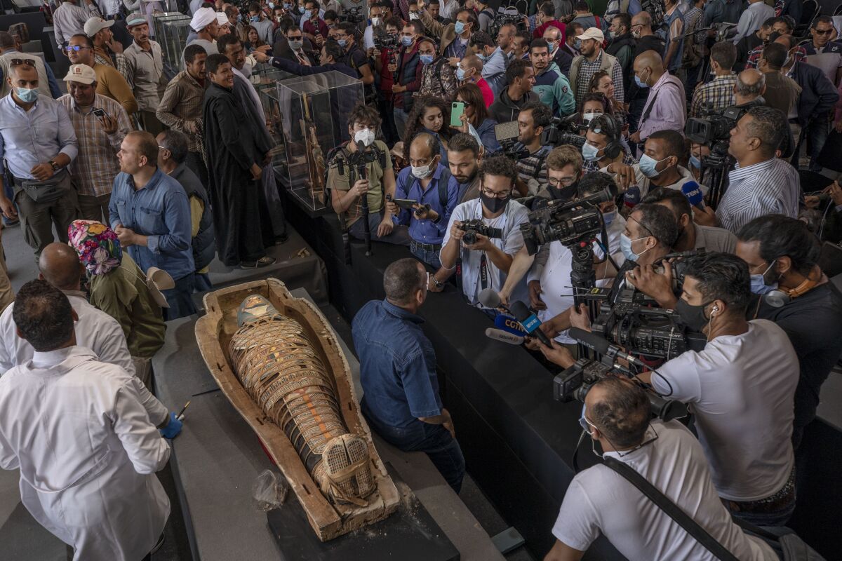 Journalists gather around an ancient sarcophagus more than 2500 years old, discovered in a vast necropolis and Mostafa Waziri, the secretary-general of the Supreme Council of Antiquities, center, in Saqqara, Giza, Egypt, Saturday, Nov. 14, 2020. Egyptian antiquities officials on Saturday announced the discovery of at least 100 ancient coffins, some with mummies inside, and around 40 gilded statues south of Cairo. (AP Photo/Nariman El-Mofty)
