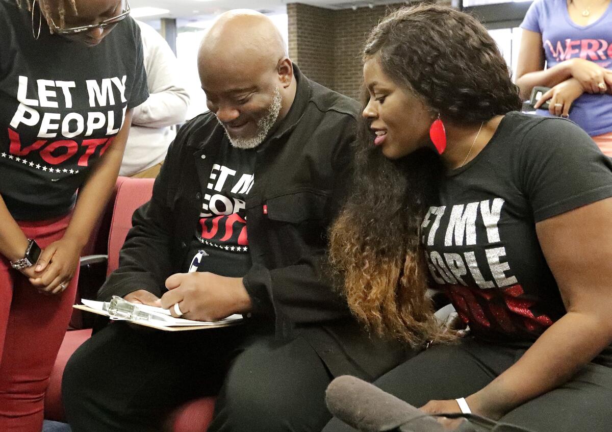 Former felon Desmond Meade fills out a voter registration form as his wife, Sheena, looks on in Orlando, Fla., in 2019.