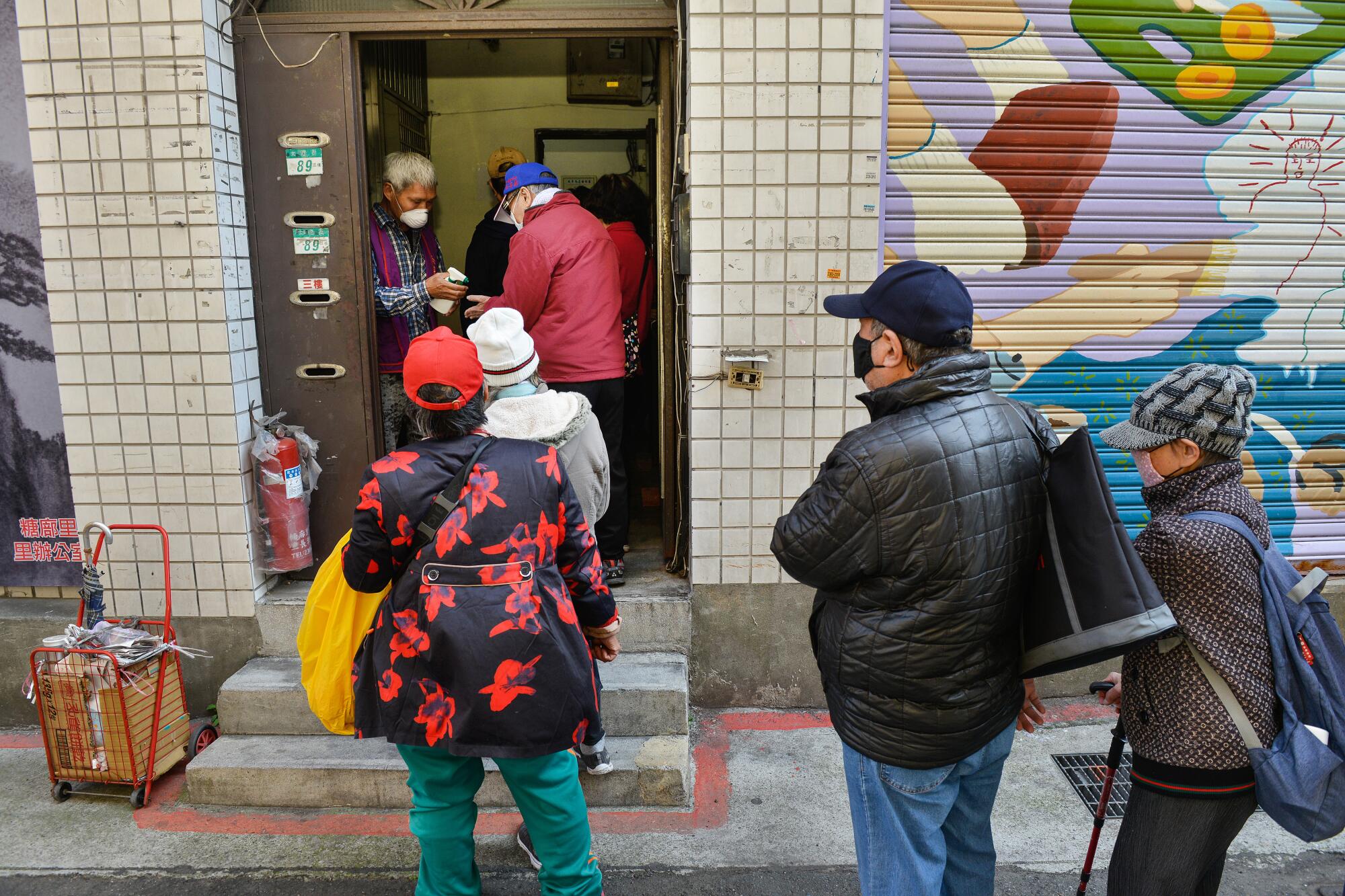 Low-income people queue up to receive one of the twice-daily meals in Taipei's Wanhua District.
