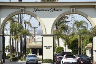 Cars drive through the double archway entrance to Paramount Pictures. 
