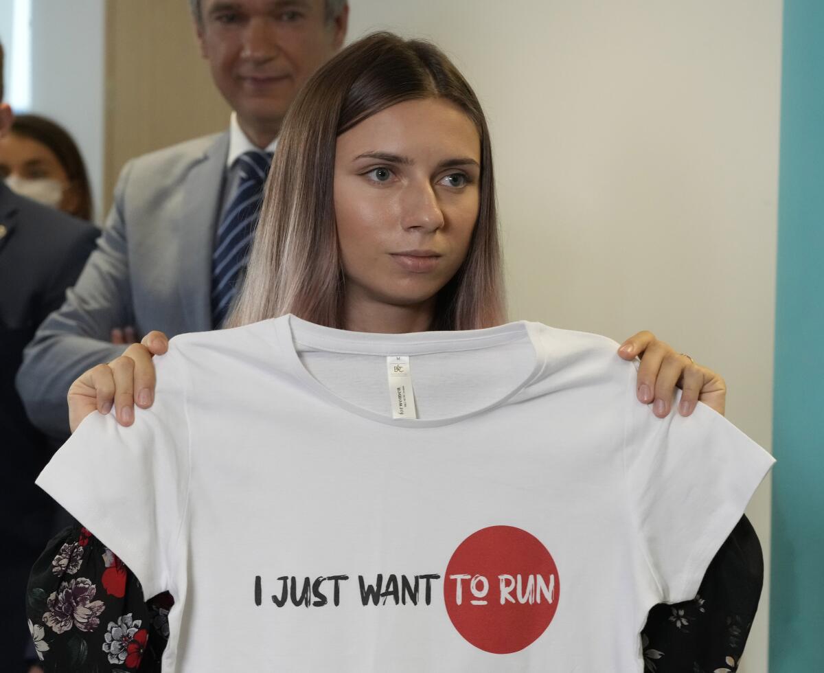 Olympic sprinter Krystsina Tsimanouskaya of Belarus holds a T-shirt reading "I just want to run."