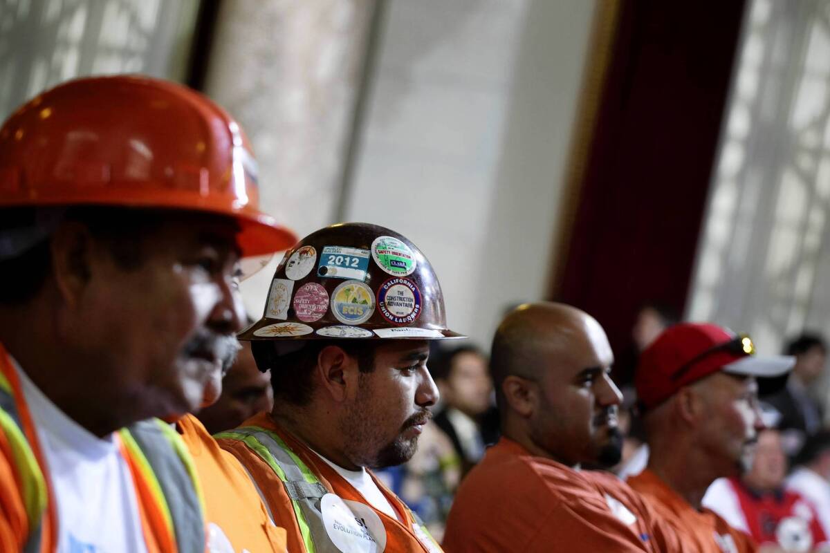 Union member Francisco Gonzalez, center in hard hat with stickers, shows support for a new trash franchise system in the city of Los Angeles.