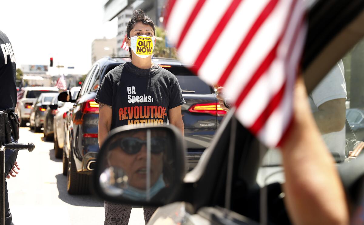 Maya Cruz with Revolution Club LA blocks a car taking part in the protest to reopen the economy along Spring Street in Los Angeles.